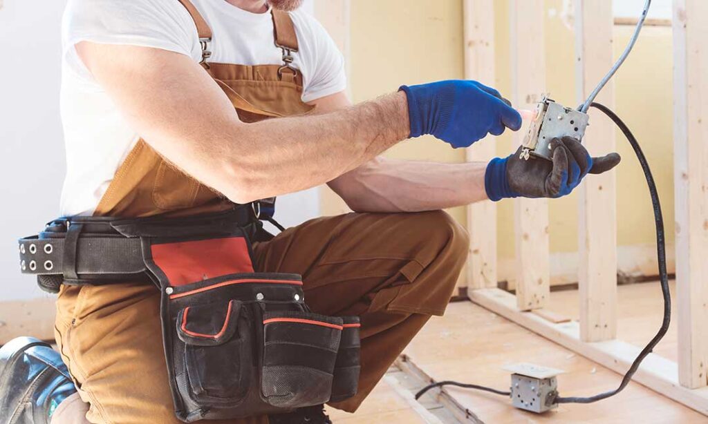 A person carefully replacing a standard light switch cover with the power turned off, using a screwdriver.