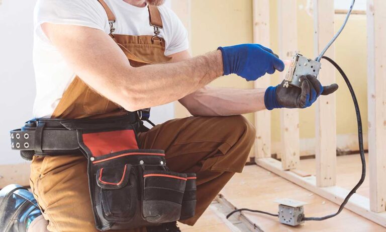 A person carefully replacing a standard light switch cover with the power turned off, using a screwdriver.