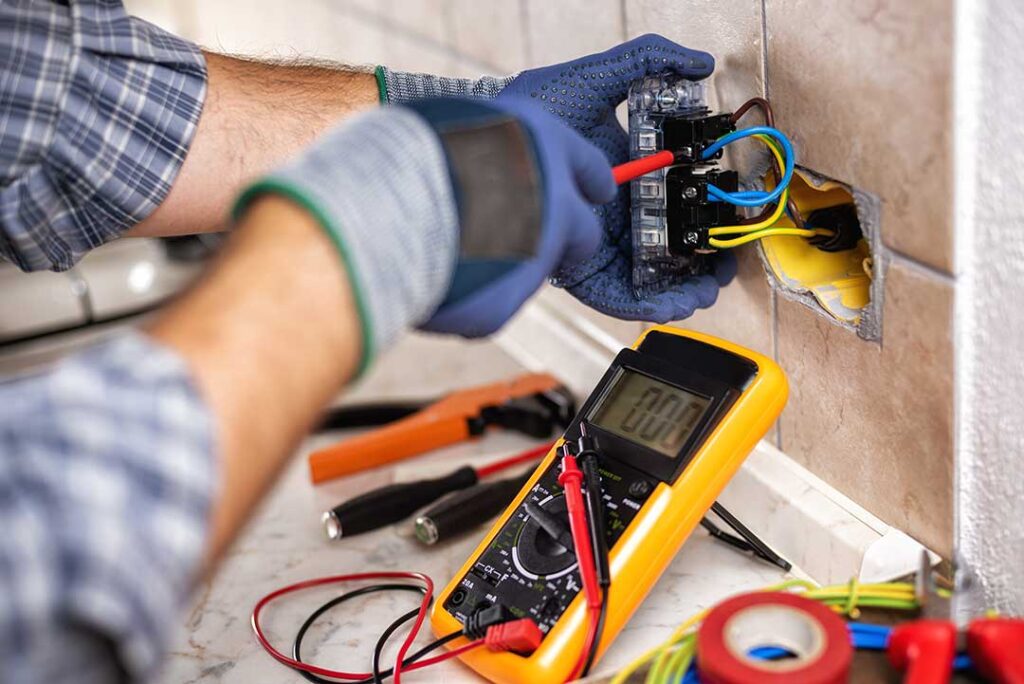 A person inspecting an open electrical panel with visible circuit breakers and labeled wiring.