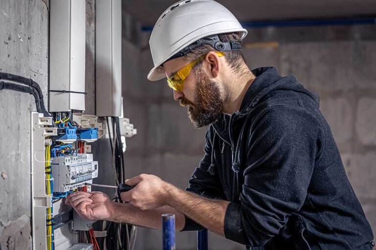 A person examining a residential electrical panel with labeled circuit breakers in a finished basement.