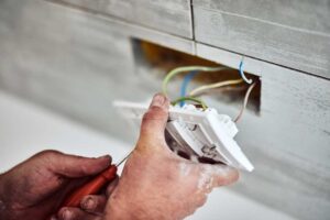 Person pressing the test button on a ceiling-mounted smoke detector inside a home.